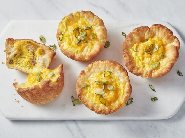 White cutting board with individual biscuit quiche viewed from above on white marble counter