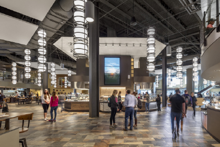 Interior image of Kansas Stat University’s Kramer Dining Center with students engaging in conversation in groups.